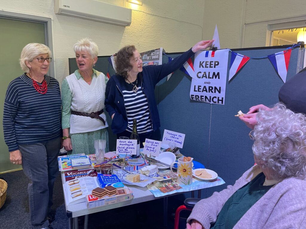 French flags, three women, table with French cheese a and biscuits
