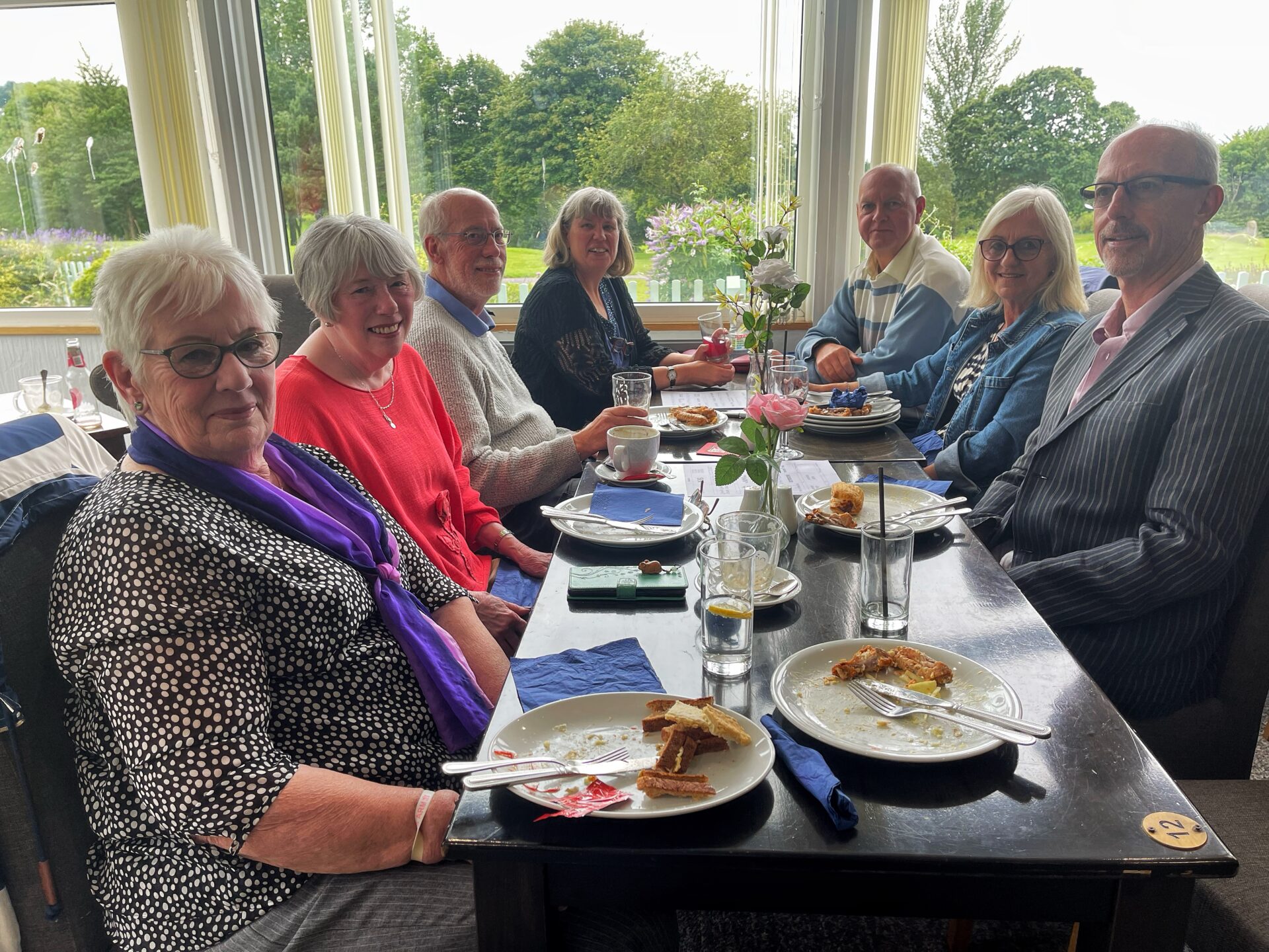people, table, plates of food, glasses,